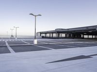 a empty parking lot with a very tall building in the background and streetlights on each side