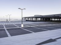 a empty parking lot with a very tall building in the background and streetlights on each side