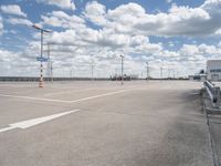 the empty parking lot is near some building and cloudy skies at daytimes time on the day