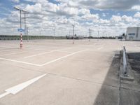 the empty parking lot is near some building and cloudy skies at daytimes time on the day