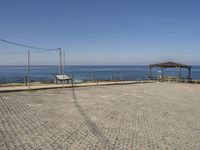 an empty parking lot next to a bench and an open air covered area at the beach