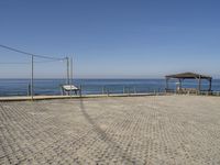 an empty parking lot next to a bench and an open air covered area at the beach