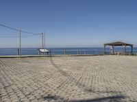 an empty parking lot next to a bench and an open air covered area at the beach