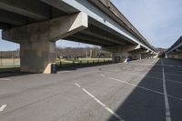 empty parking lot with concrete bridge overpassed roadways with buildings and tennis court