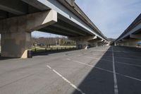 empty parking lot with concrete bridge overpassed roadways with buildings and tennis court