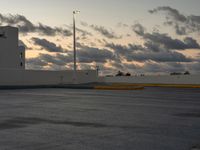 this parking lot is empty but the sky is very cloudy as the sun sets over it