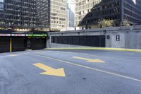 an empty parking lot with yellow arrows painted on it in the city center of a city