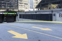 an empty parking lot with yellow arrows painted on it in the city center of a city