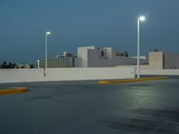 a empty parking lot with some lights on it's sides in the city at dusk