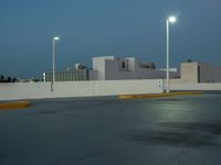 a empty parking lot with some lights on it's sides in the city at dusk