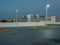 a empty parking lot with some lights on it's sides in the city at dusk