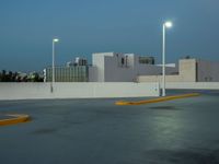 a empty parking lot with some lights on it's sides in the city at dusk