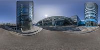 fish eye view of an empty parking lot in a city with large buildings on each side and sky in the background