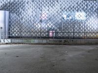 an empty parking lot with a fence and graffiti on it in front of an office building