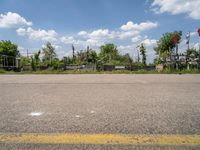 an empty parking lot with benches and flags in the distance, and some weeds in the background