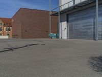 a empty parking lot near a garage door and brick wall wall and the road is paved in between it