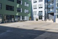 a large empty parking lot and a green building in the background with people walking up it