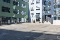 a large empty parking lot and a green building in the background with people walking up it