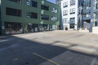 a large empty parking lot and a green building in the background with people walking up it