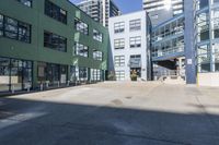 a large empty parking lot and a green building in the background with people walking up it