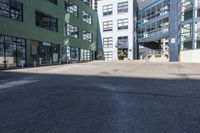 a large empty parking lot and a green building in the background with people walking up it