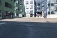 a large empty parking lot and a green building in the background with people walking up it