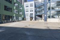 a large empty parking lot and a green building in the background with people walking up it