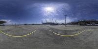 fisheye - lens view of an empty parking lot with a cloudy sky behind it