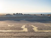 a parking lot with an empty parking lot on the beach and the ocean in the background