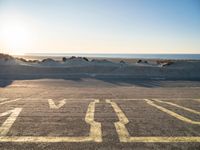 a parking lot with an empty parking lot on the beach and the ocean in the background