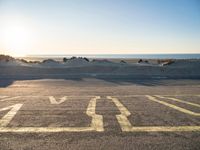 a parking lot with an empty parking lot on the beach and the ocean in the background