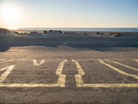 a parking lot with an empty parking lot on the beach and the ocean in the background