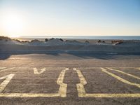 a parking lot with an empty parking lot on the beach and the ocean in the background