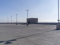 an empty parking lot with multiple posts and light poles in the background, on a sunny day