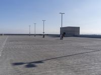 an empty parking lot with multiple posts and light poles in the background, on a sunny day