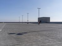 an empty parking lot with multiple posts and light poles in the background, on a sunny day