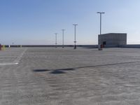 an empty parking lot with multiple posts and light poles in the background, on a sunny day