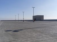 an empty parking lot with multiple posts and light poles in the background, on a sunny day