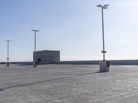 an empty parking lot with multiple posts and light poles in the background, on a sunny day