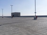 an empty parking lot with multiple posts and light poles in the background, on a sunny day