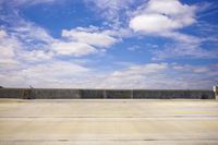 an empty parking lot in front of some buildings and water lines with a sky background