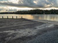 there is an empty parking lot near the lake in front of the trees in the evening