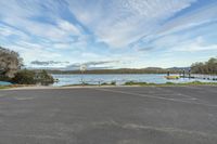 the empty parking lot by the lake has boats parked on it's poles near the shoreline