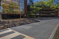 empty parking lot next to large building with reflection on building glass windows, in the shade