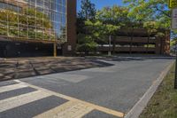 empty parking lot next to large building with reflection on building glass windows, in the shade