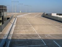 an empty parking lot has parking space on each side of the road and lights on top