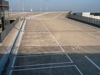 an empty parking lot has parking space on each side of the road and lights on top