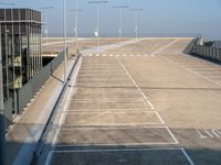 an empty parking lot has parking space on each side of the road and lights on top