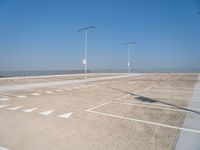 a empty parking lot with lines painted on it and a large sky over the ocean