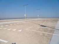 a empty parking lot with lines painted on it and a large sky over the ocean